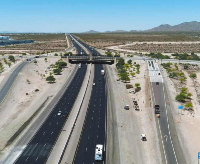 A multi-lane interstate highway cuts through a desert landscape.
