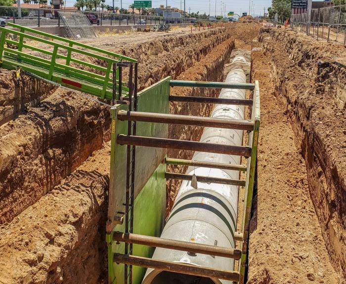 Construction of an underground drainage system. A concrete pipe is partially buried in the ground.