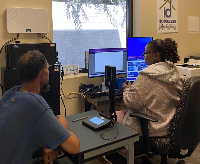 A woman works on a computer, while a man sits across the table from her.