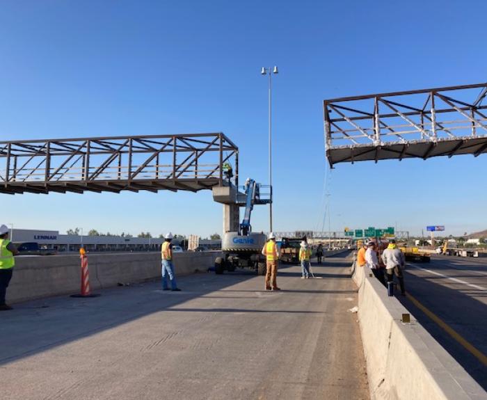 Bridge trusses are constructed above a highway.