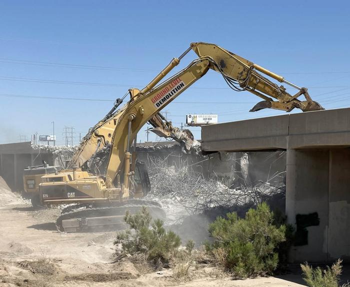 Construction heavy equipment demos a bridge.