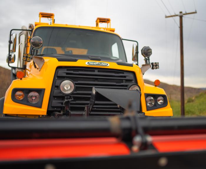 A close up of a snowplow with mountains in the background