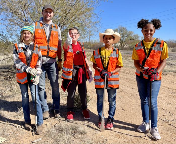 Five people dressed in orange vests volunteering to clean up the highway