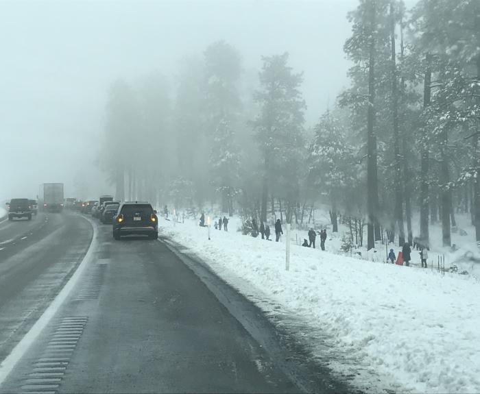 People playing in the snow along a highway shoulder