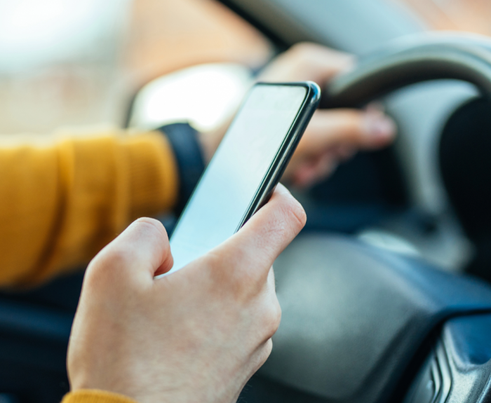 A person uses a mobile phone while driving a vehicle. 