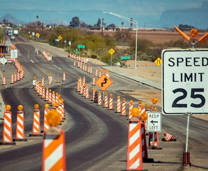 A highway work zone with orange traffic control devices.