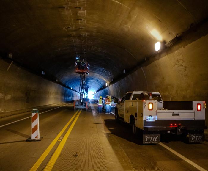 A work truck is parked inside a tunnel as construction work occurs inside the tunnel.