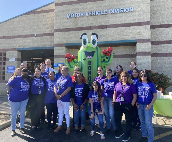 A group of people gather for a photo outside of a building.