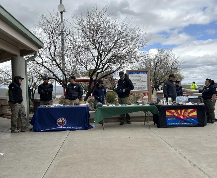 A row of display tables and wildland fire prevention officers at a rest stop.
