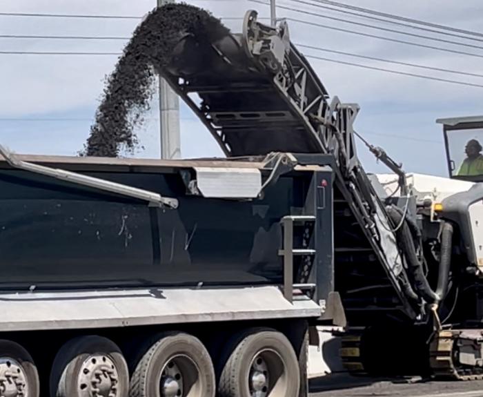 Milling machine's ramp pours asphalt into dump truck