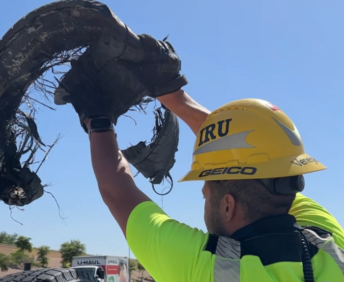 A worker putting a piece of tire debris in the back of a truck