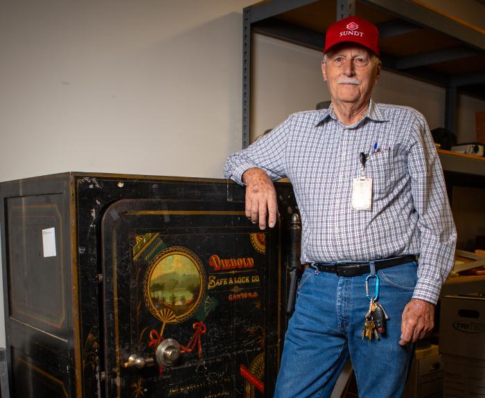 A man stands next to an old safe.