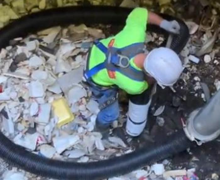 A man removes trash and debris from a pump station.