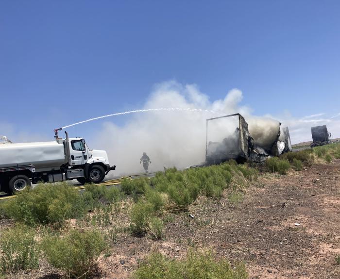 A water tanker puts out a vehicle fire on the highway