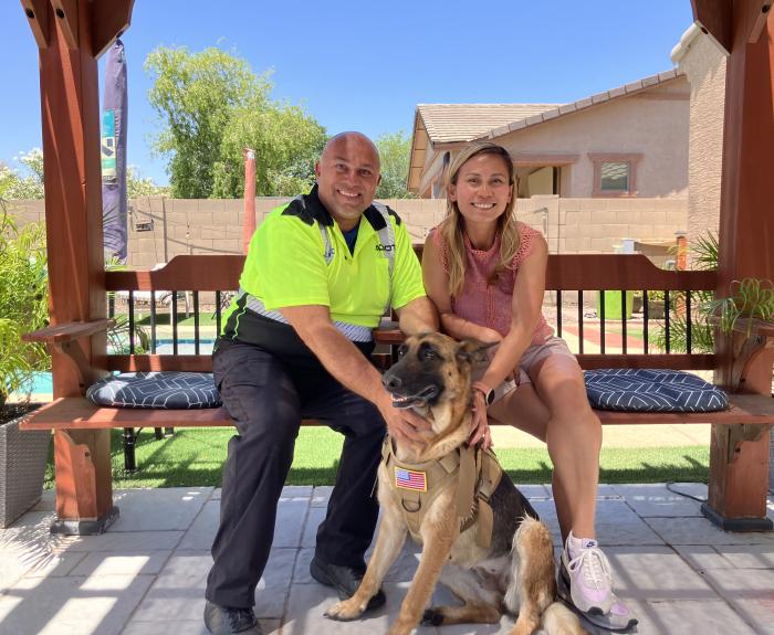 Two people pose for a picture with a dog.