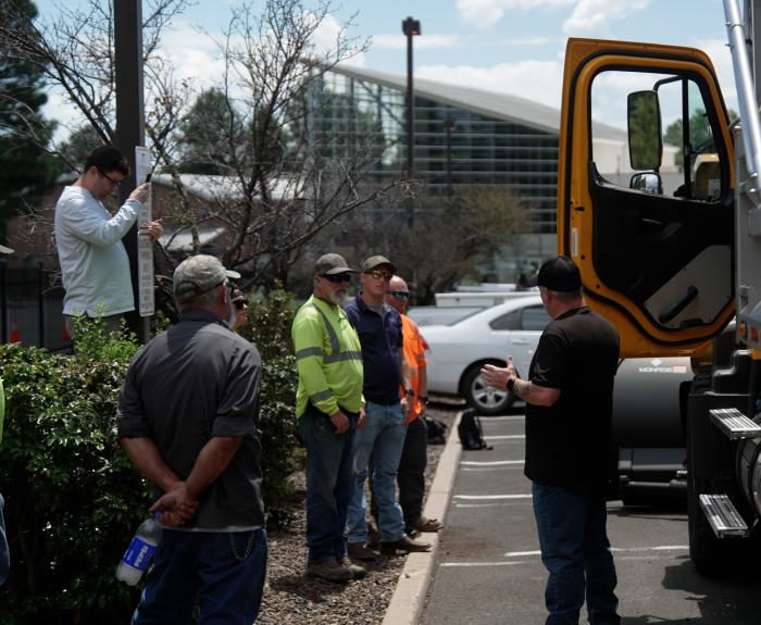 A group of employees observing an instructor in front of a snowplow