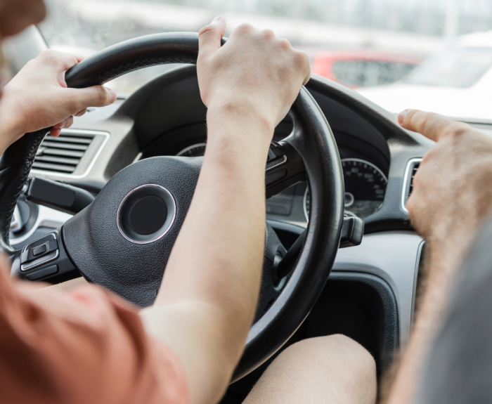 A person in the passenger seat pointing at a young driver