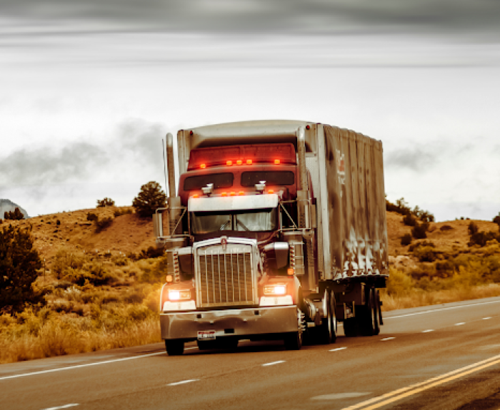 A semi-truck drivers on a rural highway.