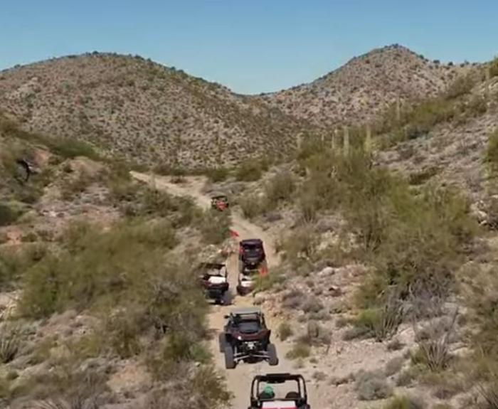 Off-highway vehicles travel together on a dirt trail.