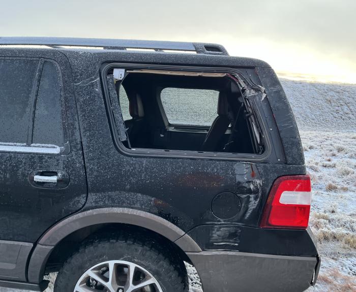 An SUV with a broken rear window after it clipped a snowplow.