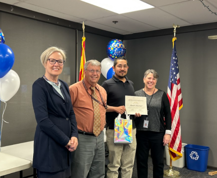 A group of people pose for a photo. One is holding a certificate.