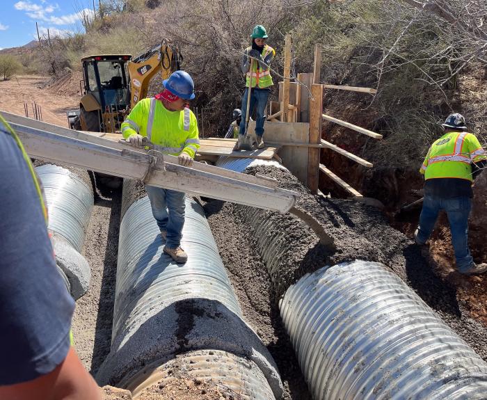 Workers pouring concrete and laying pipe