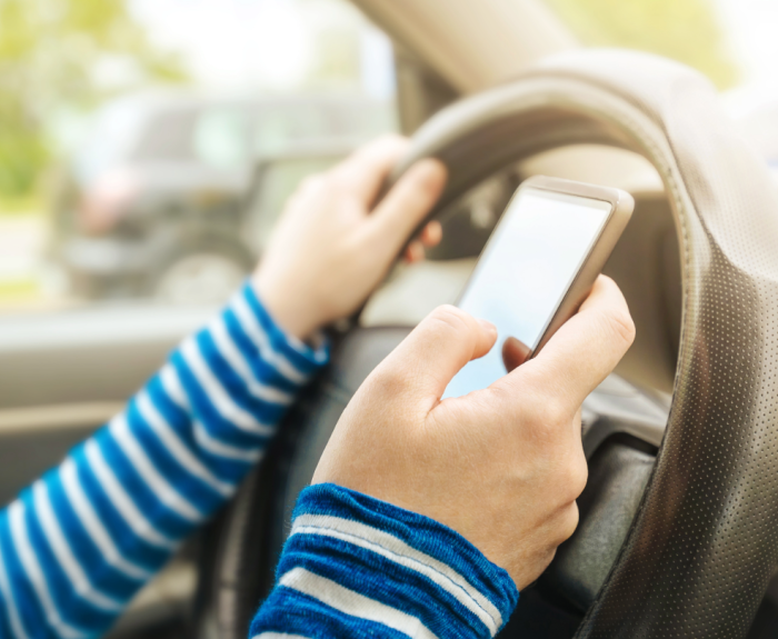 A person using a phone while driving behind the wheel.
