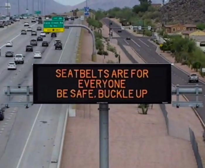 A digital message board on the highway encourages motorists to wear a seatbelt.