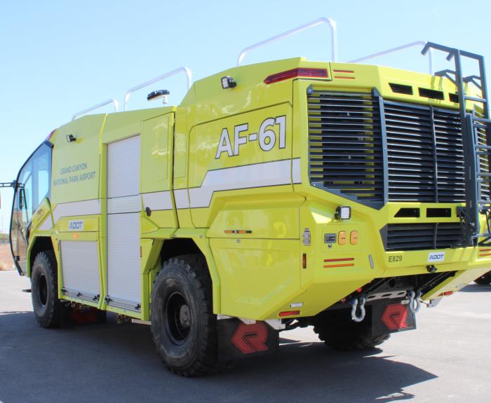 A yellow airport fire truck, labeled AF-61, is parked on asphalt under a clear sky.
