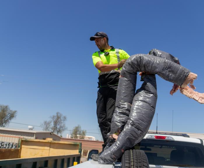 A man throwing duct work debris into a garbage dump