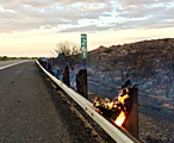 Wooden guardrail support on fire