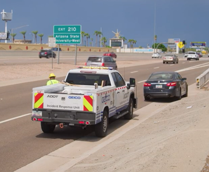 An Incident Response Unit truck assists a stranded vehicle on an urban freeway.