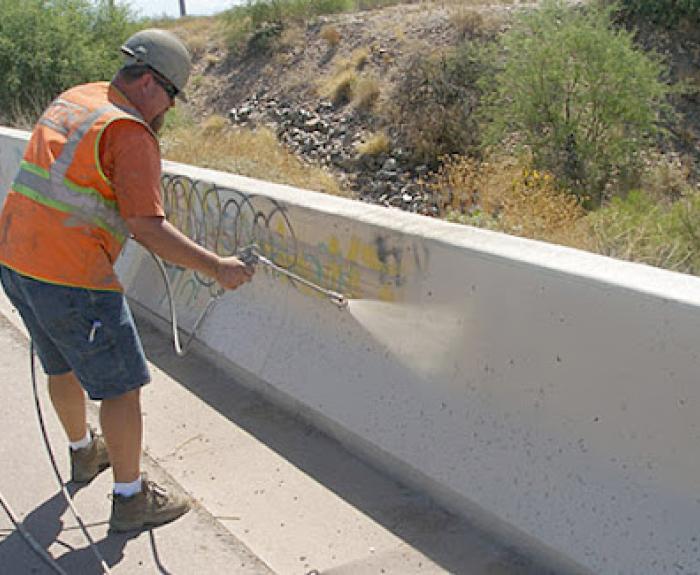 ADOT crew member is removing graffiti on overpass road