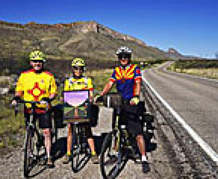 Three bike riders alongside freeway wearing helmets