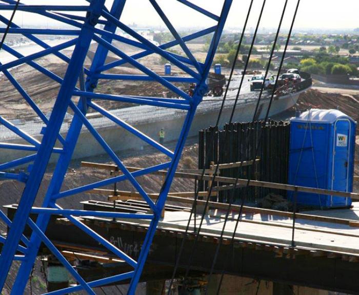 Blue construction crane and blue portable restroom