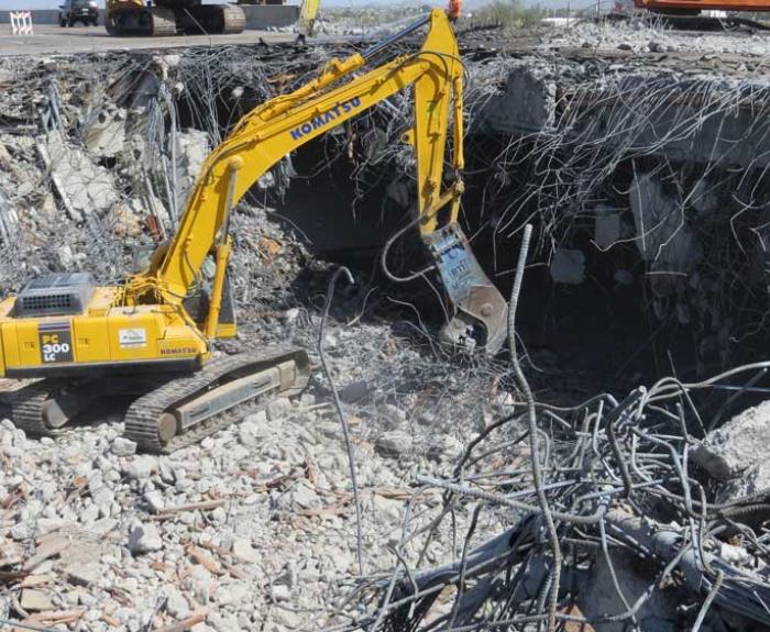 Cable, rebar, concrete and yellow backhoe.