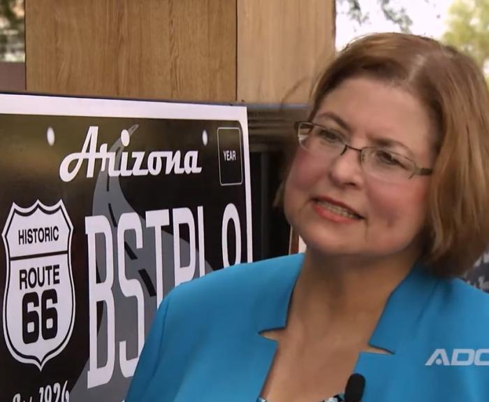 Cyndi McCabe next to representation of Route 66 license plate