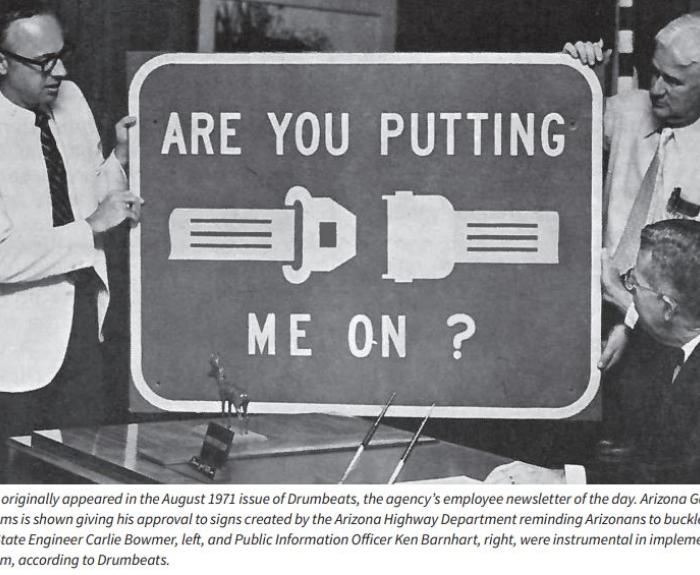 Old Seatbelt sign held by three men