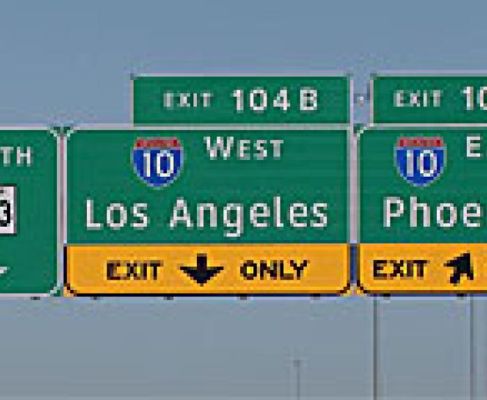 Highway signs showing directions for North 303, I-10 West to Los Angeles via Exit 104B, and I-10 East to Phoenix via Exit 104A.