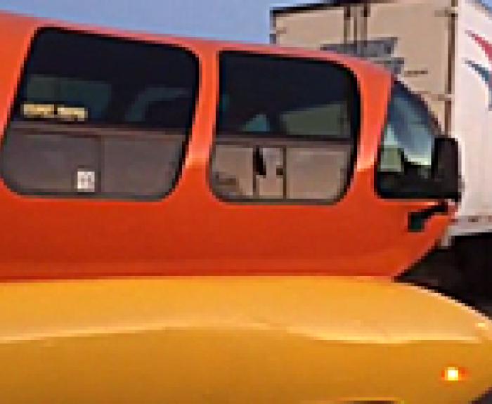 Hot dog weiner mobile on the road next to a semi-truck