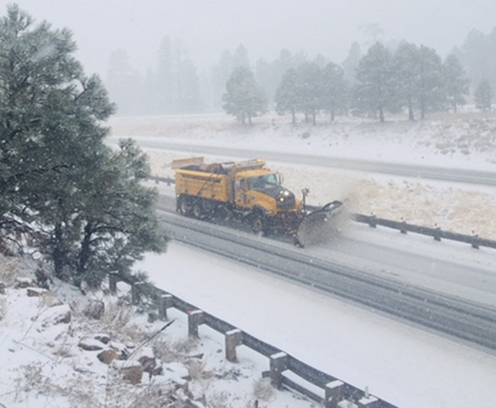 ADOT snowplow at work along snow-covered freeway