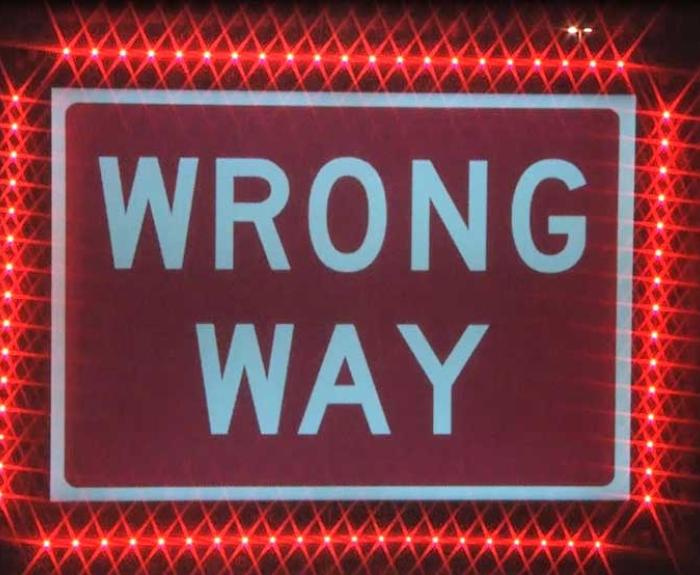 Wrong way sign lit up with red lights all around it.
