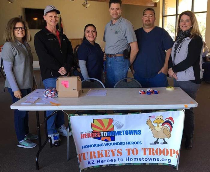 Six people standing behind a table with a banner that says Turkeys for troops