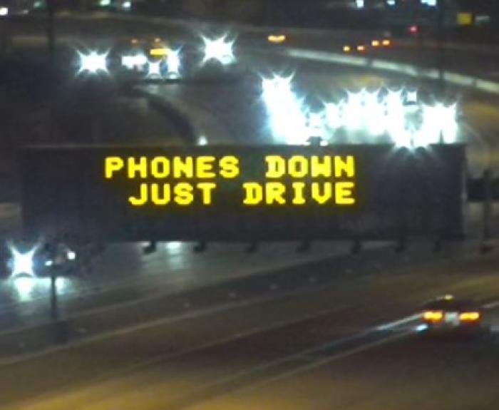 Freeway board safety message saying "Phones down"
