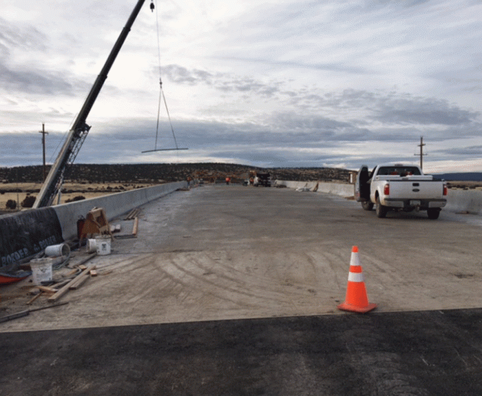 Construction scene at the West Seligman Bridges on Interstate 40 with a crane, equipment, traffic cone, and a white pickup truck.