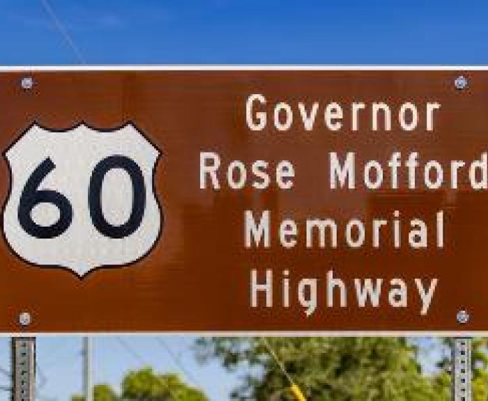 Brown road sign reads: 60 Governor Rose Mofford Memorial Highway against a blue sky.