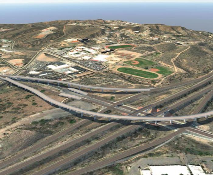 Aerial view of the Arizona Route 189 interchange with multiple overpasses surrounded by hilly terrain and buildings.