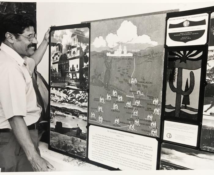 Black and white image of man looking at display board