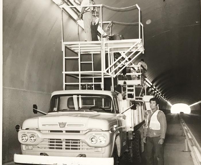 Black and white photo of workers replacing lights in the Queen Creek Tunnel