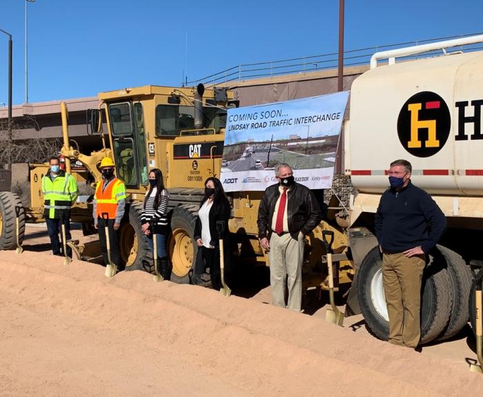Groundbreaking participants in front of large trucks